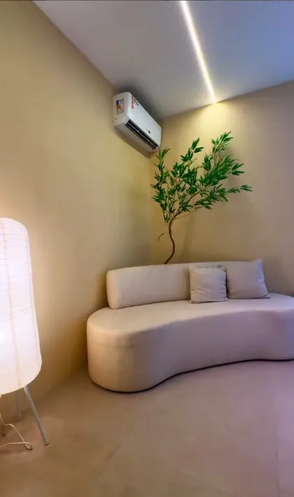 Sala de espera da M.O.N Clínica Boutique, com sofá curvo, luminária e planta